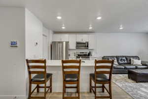 Kitchen featuring open floor plan, recessed lighting, appliances with stainless steel finishes, a breakfast bar area, and light wood finished floors