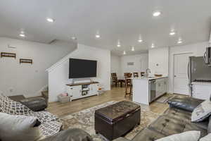 Living area featuring recessed lighting, stairway, baseboards, and light wood finished floors