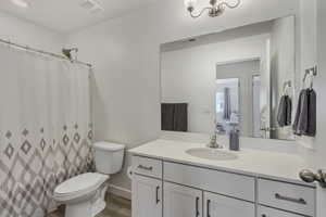 Full bath featuring visible vents, toilet, wood finished floors, and vanity