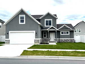 View of front facade featuring stone siding, stucco siding, and concrete driveway
