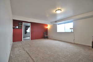 Carpeted family room with a large windows and a bedroom and storage room adjacent.  This space is connected to the main home and not part of the ADU.