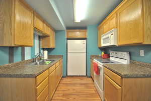 Secondary Kitchen with a sink, white appliances, dark countertops, and light wood finished floors