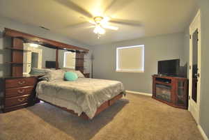 Bedroom with visible vents, carpet floors, baseboards, and ceiling fan.  Features large walk in closet. This bedroom is in the ADU unit and the bedroom set including the fireplace stay with the property.