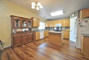 Dining area is located in the great room between the family room and kitchen, with wood-style flooring, and vaulted ceiling