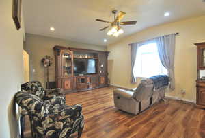 Living room featuring wood style finished floors, arched walkways, lofted ceiling, and ceiling fan.