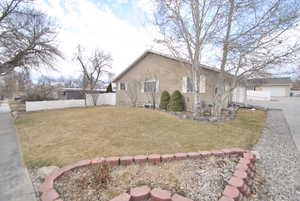 View of property exterior with fence and a lawn