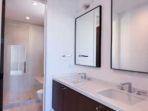 Full bath with a shower stall, double vanity, and recessed lighting