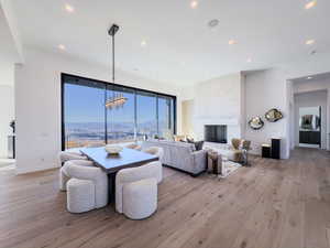 Dining space featuring a mountain view, light wood-style floors, a large fireplace, a chandelier, and recessed lighting