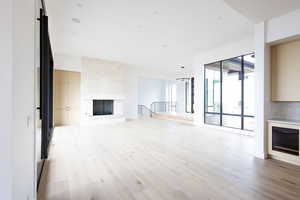 Unfurnished living room featuring a high end fireplace and light wood-style flooring