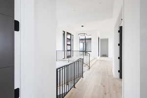 Corridor with an upstairs landing, an inviting chandelier, visible vents, and light wood-style floors
