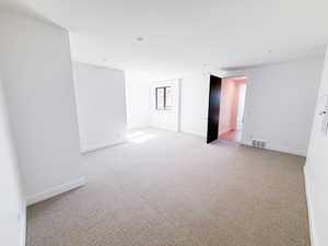 Unfurnished room featuring light carpet and baseboards