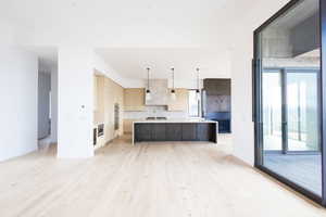 Kitchen with decorative backsplash, modern cabinets, light countertops, a sink, and light wood-style flooring