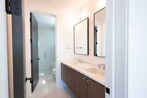 Bathroom with double vanity, a sink, toilet, and a shower stall