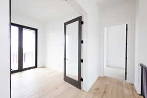 Corridor featuring french doors, light wood finished floors, and baseboards