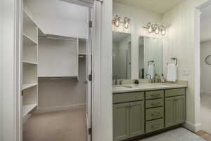 Bathroom with a sink, a walk in closet, baseboards, and double vanity