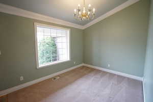 Spare room featuring visible vents, crown molding, baseboards, light carpet, and an inviting chandelier