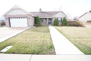 Single story home with brick siding, a chimney, concrete driveway, and fence