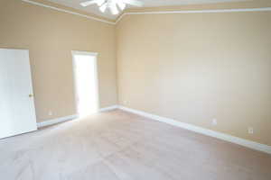 Spare room featuring baseboards, light carpet, a ceiling fan, and crown molding