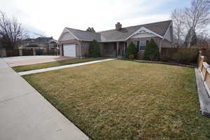 View of front facade with brick siding, concrete driveway, an attached garage, and fence