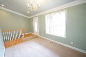 Carpeted foyer with baseboards, visible vents, an inviting chandelier, recessed lighting, and crown molding