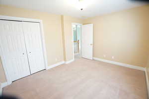 Unfurnished bedroom with baseboards, light carpet, and a closet