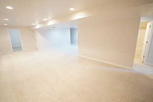 Finished below grade area with recessed lighting, baseboards, and light carpet