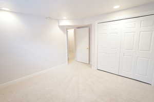 Unfurnished bedroom featuring a closet, recessed lighting, light carpet, and baseboards