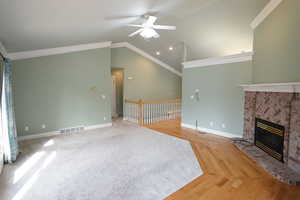 Unfurnished living room with visible vents, ornamental molding, a brick fireplace, ceiling fan, and vaulted ceiling
