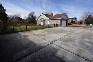 View of home's exterior featuring brick siding, fence, a lawn, a chimney, and driveway