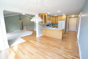 Kitchen with white appliances, visible vents, a peninsula, glass insert cabinets, and open floor plan
