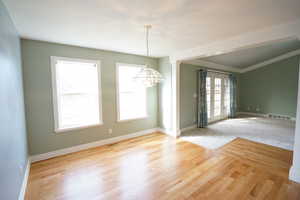 Spare room with a notable chandelier, visible vents, and plenty of natural light