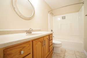Full bath featuring tile patterned floors, vanity, toilet, and  shower combination