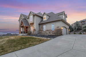 View of front of property with a lawn, stone siding, driveway, and stucco siding