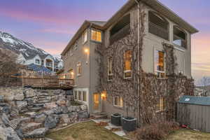 Back of house featuring a storage shed, an outdoor structure, cooling unit, and stucco siding