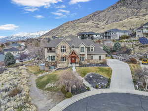 View of front facade with stone siding, a mountain view, and a front lawn