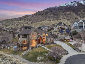 View of front of house featuring cooling unit, roof with shingles, concrete driveway, stone siding, and a mountain view