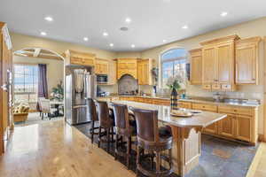 Kitchen featuring a kitchen island, recessed lighting, arched walkways, stainless steel appliances, and a kitchen bar
