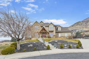 View of front of property featuring stucco siding, stone siding, and roof with shingles