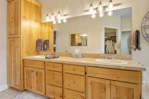 Full bath featuring tile patterned flooring, double vanity, a spacious closet, and a sink