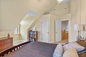 Bedroom with lofted ceiling, light colored carpet, visible vents, and baseboards