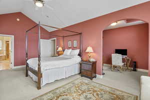 Bedroom with ensuite bath, lofted ceiling, arched walkways, and carpet floors