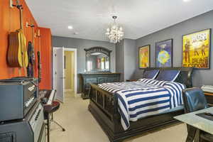 Bedroom with light colored carpet, baseboards, and a notable chandelier