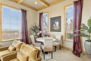 Dining area featuring beam ceiling, light colored carpet, baseboards, and a wealth of natural light