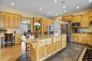 Kitchen with recessed lighting, stainless steel fridge with ice dispenser, built in microwave, and a center island