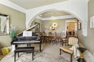 Living area with arched walkways, ornate columns, and ornamental molding