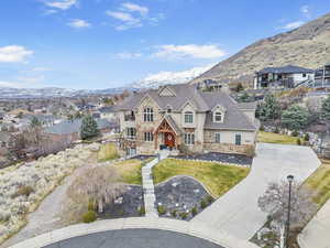 View of front of property with a front lawn, a residential view, stucco siding, stone siding, and a mountain view