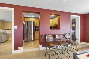 Dining space with a textured ceiling, light tile patterned floors, baseboards, and light carpet