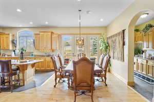 Dining area with recessed lighting, baseboards, arched walkways, and light wood-style floors