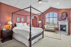 Carpeted bedroom with visible vents, a glass covered fireplace, recessed lighting, lofted ceiling, and ceiling fan