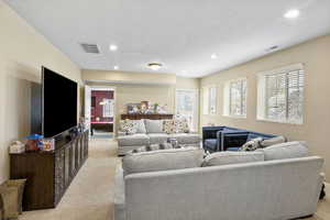 Living area featuring recessed lighting, visible vents, light carpet, and a textured ceiling